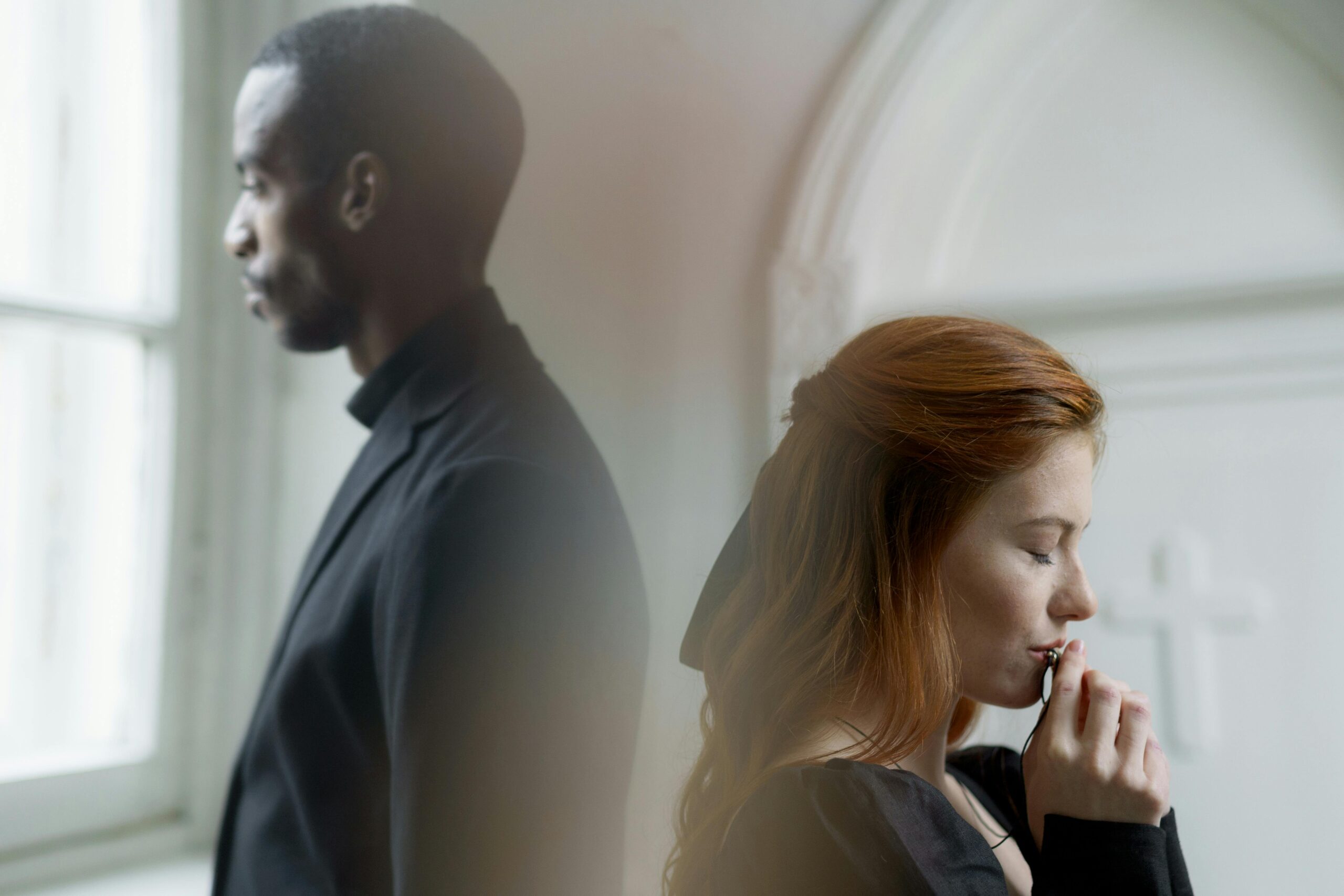 Two individuals in deep thought, captured in a serene indoor setting.